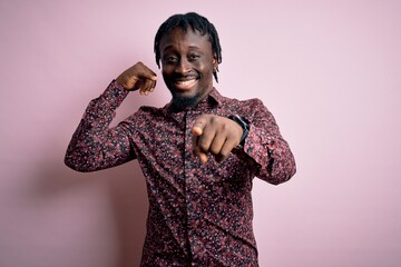 Young handsome african american man wearing casual shirt standing over pink background smiling doing talking on the telephone gesture and pointing to you. Call me.