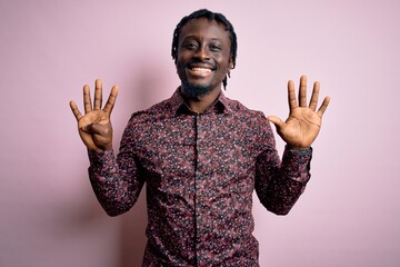 Young handsome african american man wearing casual shirt standing over pink background showing and...