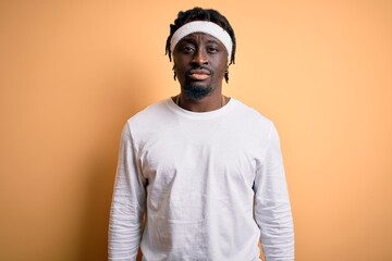 Young african american man doing sport wearing sportswer over isolated yellow background with serious expression on face. Simple and natural looking at the camera.