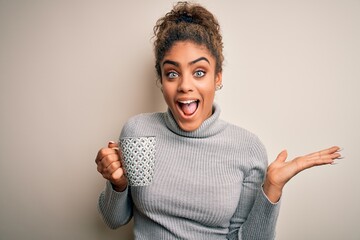 Young african american afro girl drinking cup of coffee over isolated white background very happy and excited, winner expression celebrating victory screaming with big smile and raised hands