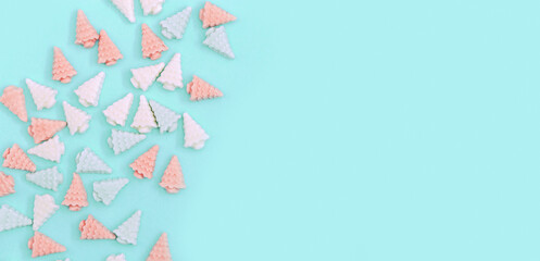 Pastel cute chocolate candies, sweets in form of Christmas trees. Banner with  New Year pattern in mint pink pastel tones on paper background minimal style. Top view.