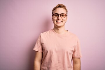 Young handsome redhead man wearing casual t-shirt standing over isolated pink background with a happy and cool smile on face. Lucky person.