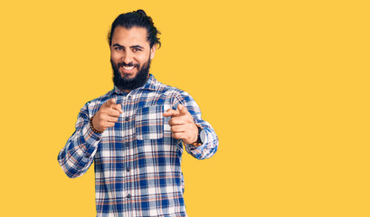 Young arab man wearing casual clothes pointing fingers to camera with happy and funny face. good energy and vibes.