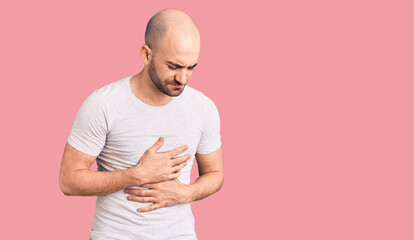 Young handsome man wearing casual t shirt with hand on stomach because indigestion, painful illness...