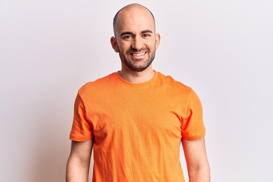 Young handsome bald man wearing casual t shirt with a happy and cool smile on face. lucky person.