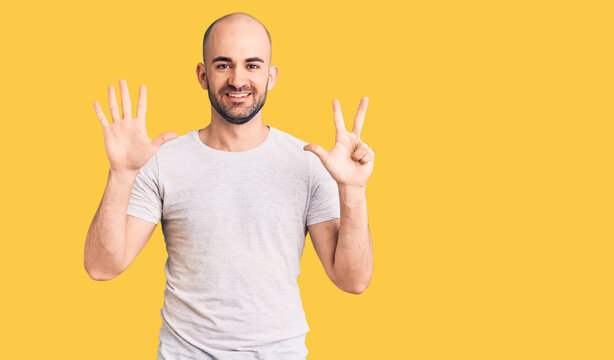 Young handsome man wearing casual t shirt showing and pointing up with fingers number eight while smiling confident and happy.