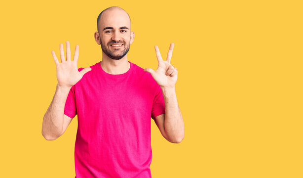 Young handsome man wearing casual t shirt showing and pointing up with fingers number eight while smiling confident and happy.