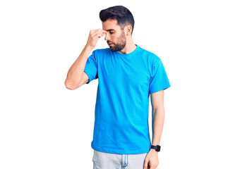 Fototapeta premium Young handsome man with beard wearing casual t-shirt tired rubbing nose and eyes feeling fatigue and headache. stress and frustration concept.