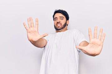 Fototapeta premium Young hispanic man wearing casual clothes afraid and terrified with fear expression stop gesture with hands, shouting in shock. panic concept.