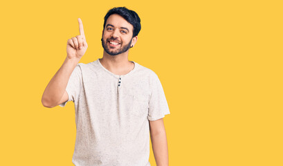 Young hispanic man wearing casual clothes showing and pointing up with finger number one while smiling confident and happy.