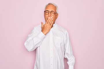 Middle age senior grey-haired man wearing glasses and business shirt over pink background bored yawning tired covering mouth with hand. Restless and sleepiness.