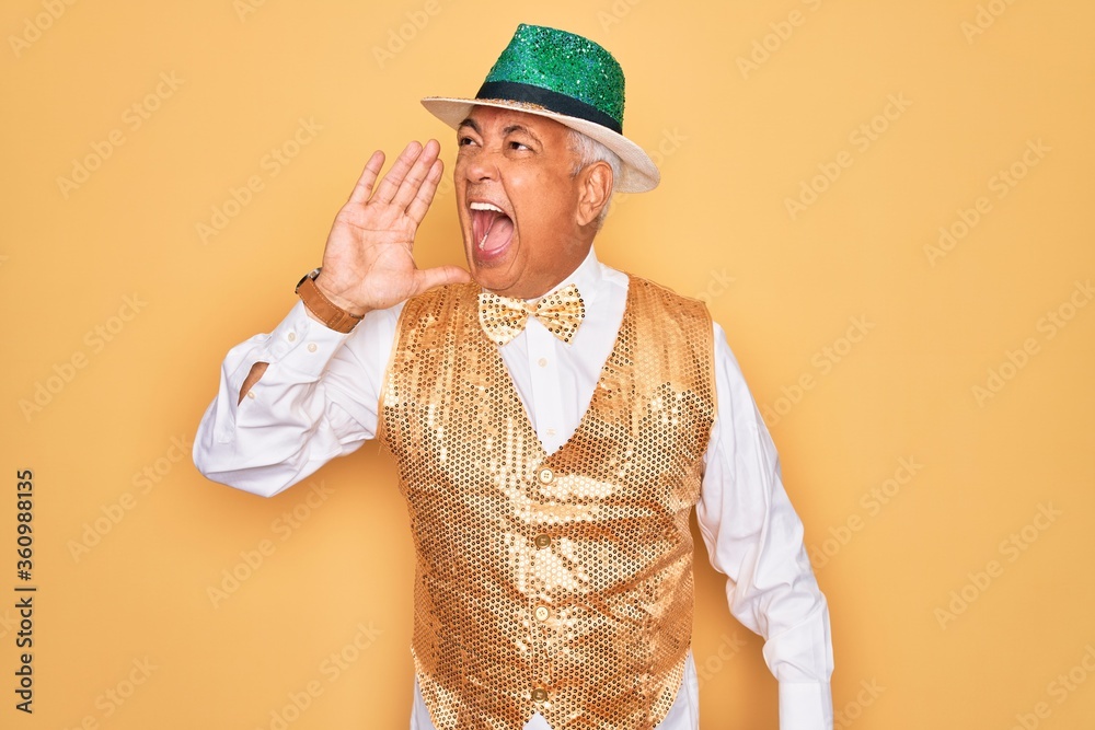 Poster Middle age senior grey-haired man wearing Brazilian carnival custome over yellow background shouting and screaming loud to side with hand on mouth. Communication concept.