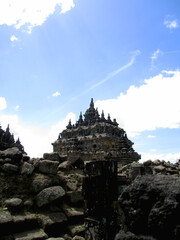Brick stone blocks and rock ruins with gates of Plaosan Temple Candi behind, with blue sky and white clouds. Area of historical landmark heritage at Klaten, Central Java, Indonesia.