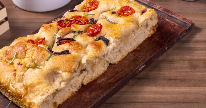 Traditional Italian Focaccia with pepperoni, cherry tomatoes, black olives, rosemary ando onion - homemade flat bread focaccia