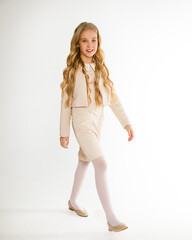 Photo of a beautiful blonde girl with long hair in curls in stylish fashionable clothes look at the camera on a white background in full growth. Isolated. School girl 8-10 years old. go back to school