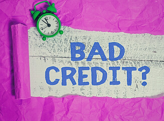 Writing note showing Bad Credit Question. Business concept for a bad credit score due to nonpayment of loans Rolled ripped torn cardboard above a wooden classic table
