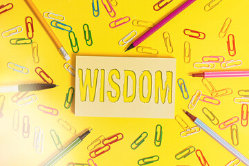 Conceptual hand writing showing Wisdom. Concept meaning body of knowledge and principles that develops within specific period Flat lay above empty paper with pencils and paper clips