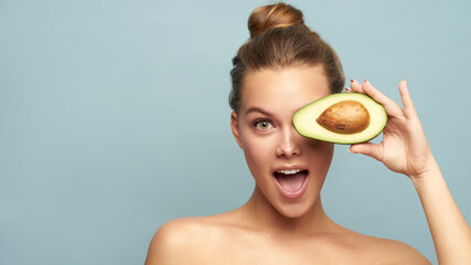 Beautiful young woman with fresh avocado on light background