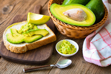 Avocado sliced and avocado toast on wooden background fruits healthy food concept - avocado dip mashed