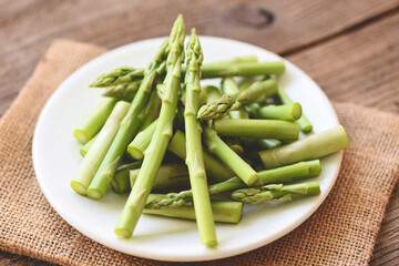 Asparagus on white plate and wooden background - Fresh green asparagus sliced for cooking food