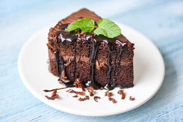 Cake chocolate sauce delicious dessert served on the table - cake slice on white plate with topping chocolate and mint leaf