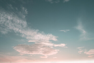 Beautiful pastel pink blue sky background with sun light rays & spectrum flares shining through soft white cirrocumulus clouds or cirrostratus cloudscape on bright daylight horizon in tropical summer 
