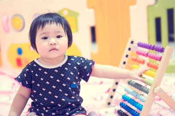 asian little adorable baby toddler girl using math montessori with colorful bead, playing and learning using hands moving each bead calculating on early age development on statistics skills concept