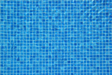 Top view of clear water in a blue tile pool background. Ripple effect