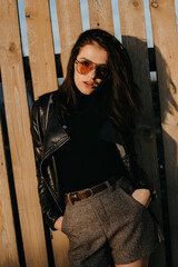 portrait of a stylish young brunette girl in sunglasses and a leather jacket