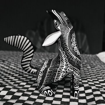 a black and white photo of a fantastic mexican hand craft ( alebrijes) of a wolf on a table