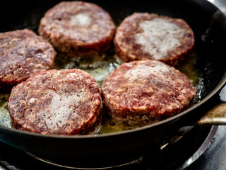 Beef burgers fried in frying pan.