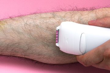 Man epilates his leg with an electric epilator device. close-up male leg shaver shaving. Skin Care and Health. Hair Removal.