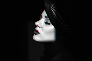 fashion portrait in profile of a young sexy girl in a black hat with lipstick