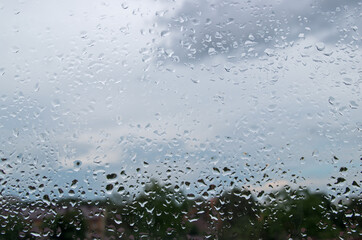 Abstract pattern consisting of randomly arranged raindrops hanging on  window pane after recent...