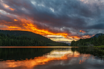Fototapeta na wymiar Amazing orange sunset over lake with reflection at Inland Lake Provincial Park on the sunshine coast near Powell River on Inland Lake Provincial park.