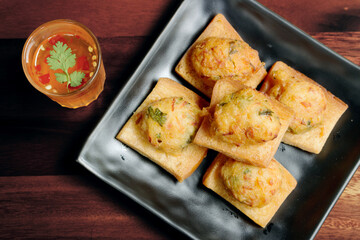 Fried Bread with Minced Pork Spread with sauce on a wooden dish, and wooden background.