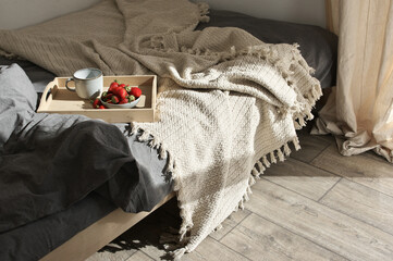 Unmade bed with breakfast at sunlight