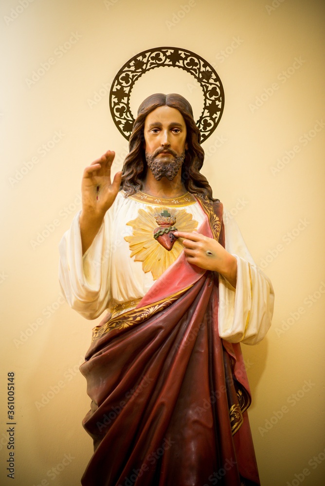 Wall mural vertical shot of a statue of jesus christ in a red robe on a yellow background