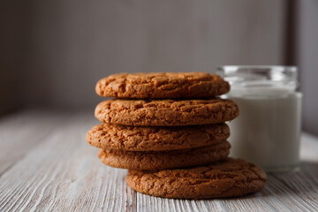 Tasty cookies and a glass of milk in a transparent glass on a rustic white background. Copy space