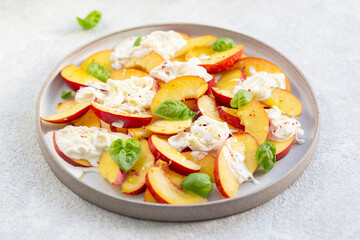 Fresh salad with peaches, Italian Stracciatella cheese, Basil, olive oil and honey. Summer salad, healthy food concept. Selective focus