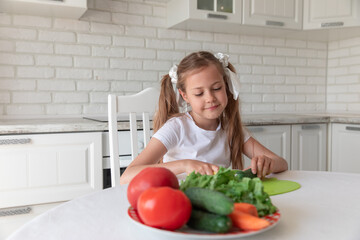 little girl in the kitchen cutting vegetables