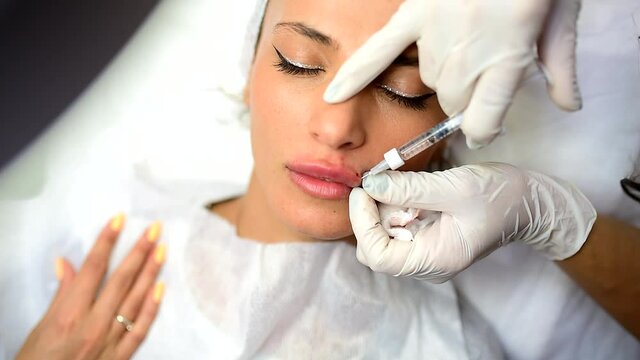 cosmetologist make injection into the womans lips. lip augmentation and plastic surgery.