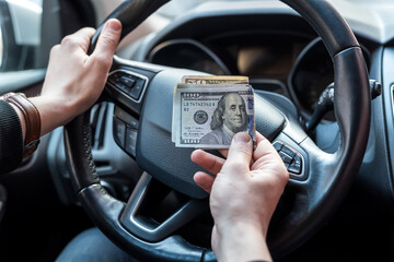 Man holding  dollars sitting in car
