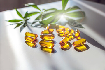 Medical cannabis products: leaf, capsules and CBD oil on white background. Pharmaceutical gelatin...