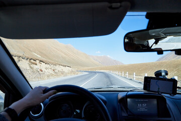 Tbilisi, Georgia - October 25, 2019: Car vindow, hand of woman on steering wheel and view to the road and autumn mountain landscape