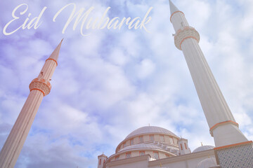 Eid Mubarak description on english and minarets of a mosque opposite cloudy blue sky