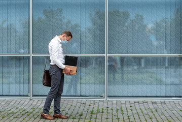 Fototapeta premium Dismissal of an employee due to epidemic of coronavirus. Dismissed employee leaves the office with his office supplies.