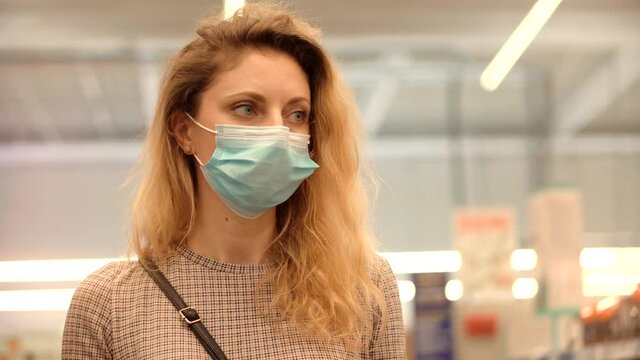 Woman Shopper Choosing Product In Hypermarket Store.Girl In Face Mask Shopping In Market On Covid19 Coronavirus Pandemic Quarantine Lock down. Bayer In Medical Mask In Supermarket Avoid Self Distance