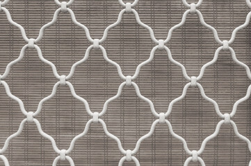 Naklejka premium Diamond shape of white curved wrought iron steel on the lattice window, gray bamboo curtain background, lattice work for house decoration