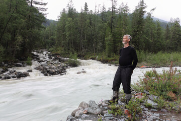 Man standing on the shore of a mountain river